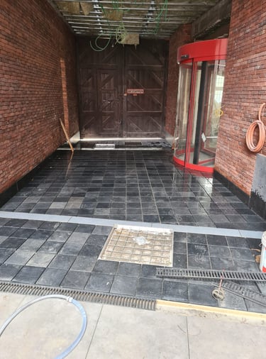 Pose de pavés en pierre naturelle dans une entrée avec grilles de drainage intégrées