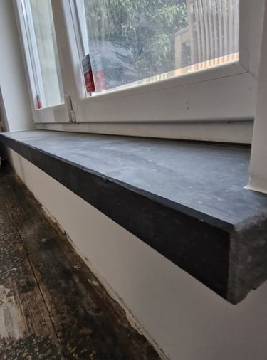 Appui de fenêtre en pierre bleue installé sous châssis PVC dans un logement rénové