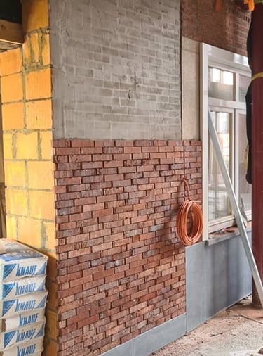 Reconstruction partielle de façade en briques avec intégration de blocs béton et isolation