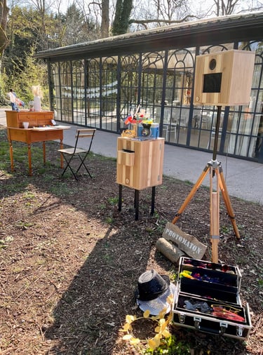 Rustic outdoor photo booth rental setup with wooden tripod and prop kit for a garden event.