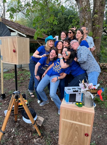 A group of friends posing for a fun outdoor photo booth with props at a birthday party celebration.