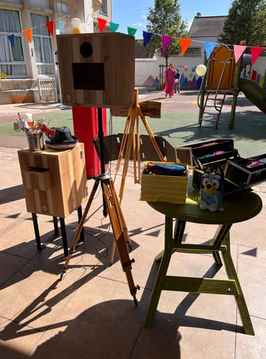 Vintage wooden photo booth with props and tripod set up for an outdoor party at a playground.
