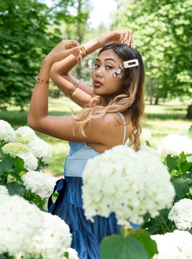 Portrait photo of a young Indonesian woman in a park with flowers and whimsical blue dress