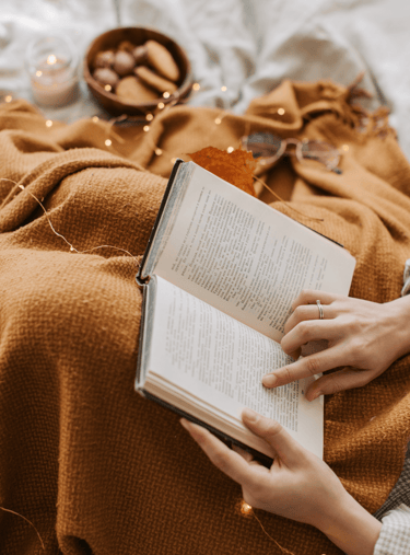 girl reading spiritual awakening book with blanket and cookies