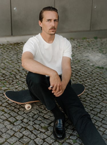 Portrait of artist and designer Philipp Schäfer sitting on a skateboard