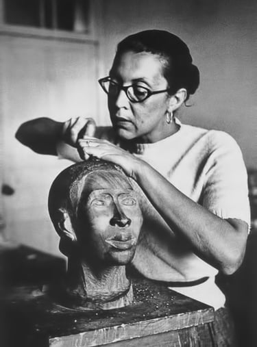 Artist Elizabeth Catlett sculpting a clay head portrait in her art studio.