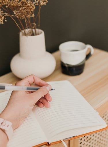 a person holding a pen and writing on a notebook