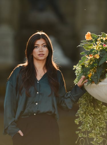 Une très belle femme pose devant une grande vasque fleurie, le soleil dans les cheveux