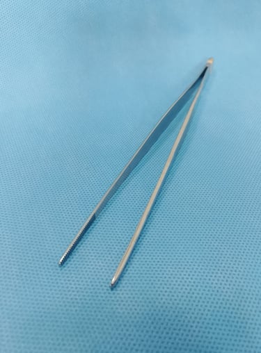 Pinça anatômica sobre tecido azul estéril, usada para manuseio delicado de tecidos.