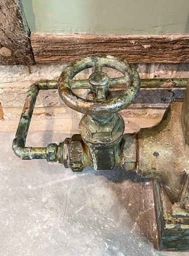 Close-up on a painted radiator valve and a painted copper pipe on antique plaster wall
