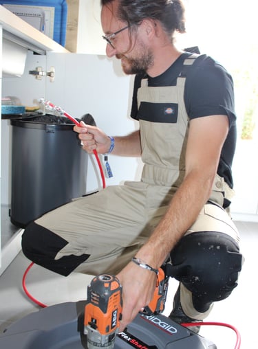 un artisan vidangeur avec un déboucheur manuel sous un évier