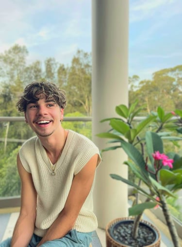 a man sitting on a balcony with a plant in front of him