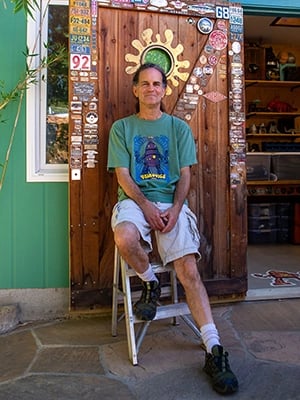 Artist Tal Avitzur sitting in front of his workshop.