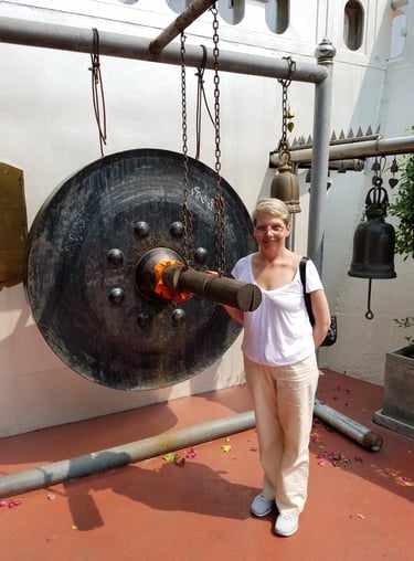 Ladi Michelle bangs the gong at Wat Saket Temple in Bangkok