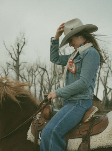 a woman in a cowboy hat sitting on a horse
