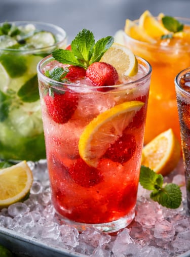 Refreshing assortment of iced cocktails and fruit mocktails with fresh mint, berries, and citrus slices.
