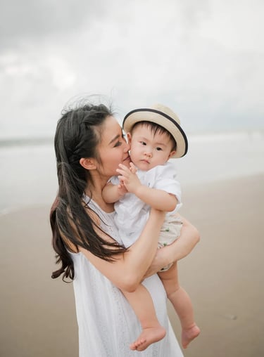 Mother holding baby during family photography session at Alila Seminyak Bali with calm beach atmosphere.