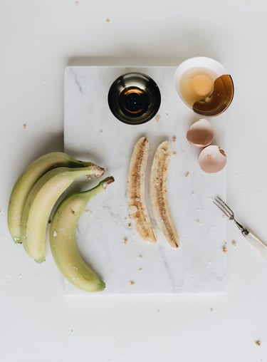 a cutting board with bananas and eggs on it