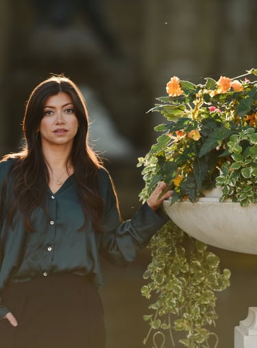Une très belle femme pose devant une grande vasque fleurie, le soleil dans les cheveux