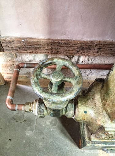 Close-up on a painted radiator valve and a new copper pipe on antique plaster wall