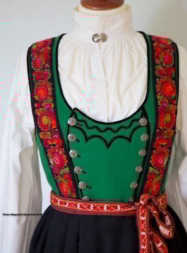 A green bodice bunad with rose embroidery on a mannequin
