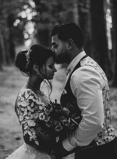 le marié qui embrasse la mariée sur le front dans une allée de platane