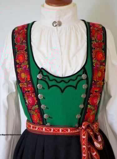 A green bodice bunad with rose embroidery on a mannequin
