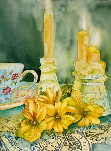 Delicate floral teacup alongside yellow flowers and golden candles in glass holders with lace cloth