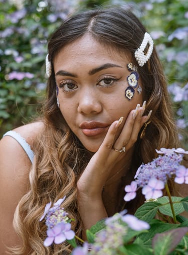 Portrait photo of a young Indonesian woman in a park with flowers and whimsical blue dress