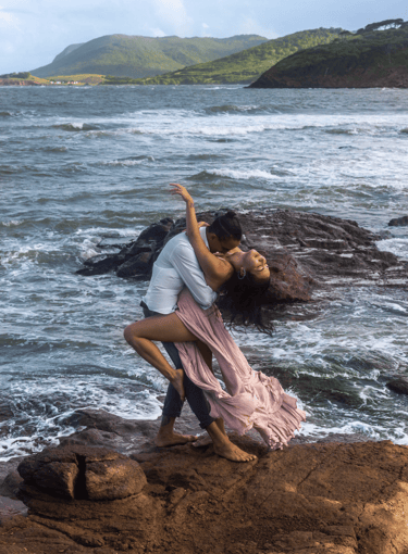 a man and woman kissing on a rock at the beach in Saint Lucia