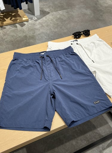 A stylish pair of capris displayed on a wooden bench with sunlight filtering through leaves.