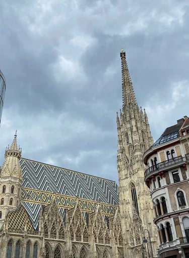 Detailed view of the iconic mosaic roof and spire of Stephansdom under a cloudy sky.