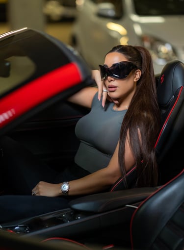 Model sitting inside a red Ferrari car wearing sunglasses, captured by Fred Art Studio.