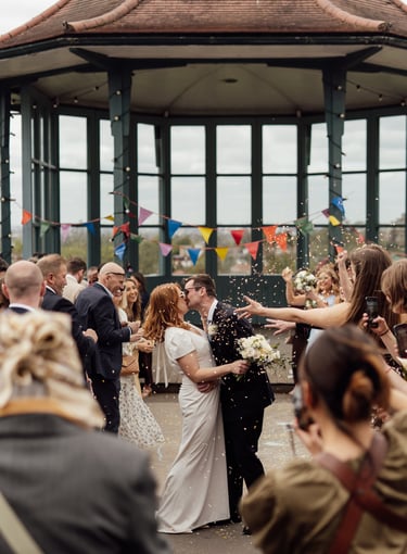 newly married couple are kissing through confetti 