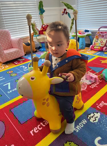 Young child sitting on a yellow inflatable giraffe