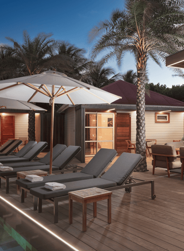 a patio with lounge chairs and umbrellas in st barth