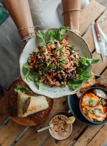 a person holding a plate with a salad on it