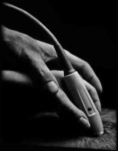 Clinical instructor's hand over the hand of the sonographer, guiding an ultrasound scan of the heart.