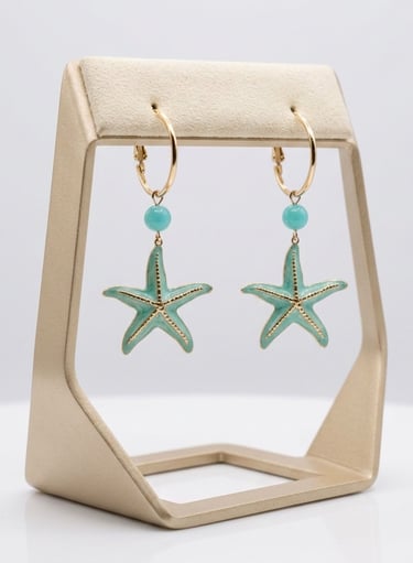 Gold hoop earrings with turquoise starfish charms and blue beads on a jewelry display stand.