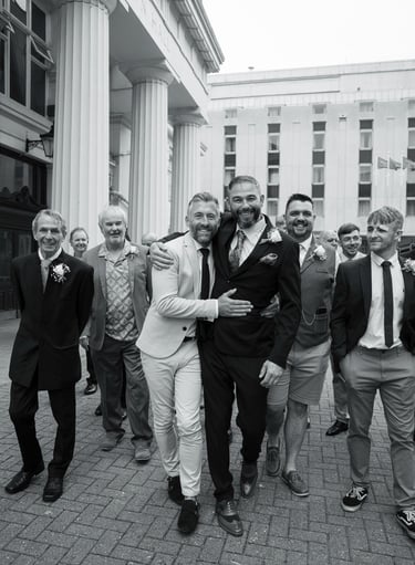 Black and white image of groom with his groomsmen laughing walking 