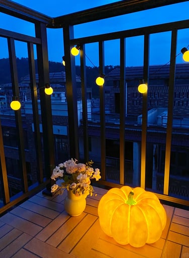 Cozy small balcony with space-saving furniture, soft cushions, potted plants, and warm evening light