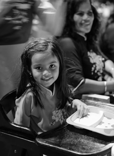 a young girl sitting in a high chair at a table