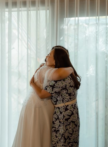 a woman in a wedding dress is hugging her mother