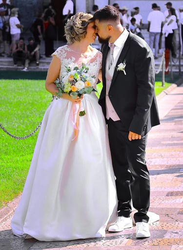 Bride and groom posing together outside a historic cathedral during their wedding ceremony on a sunny day.