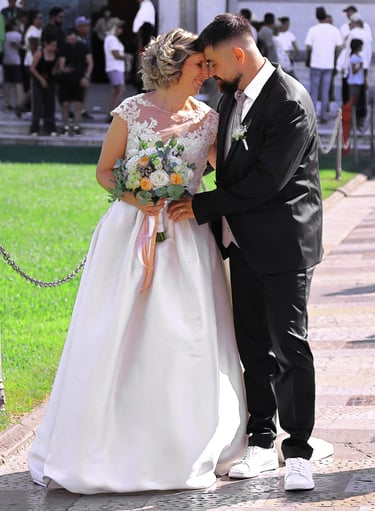 Bride and groom posing together outside a historic cathedral during their wedding ceremony on a sunny day.