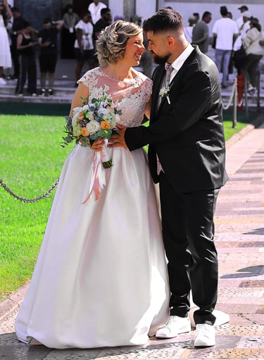 Bride and groom posing together outside a historic cathedral during their wedding ceremony on a sunny day.