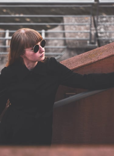 a woman in sunglasses and a black jacket standing on a stair case