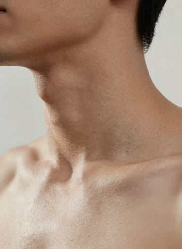 A close-up photography study of the neck and shoulder area. The skin is illuminated by a very soft, faint off-white light that creates high-contrast shadows. The aesthetic is modern and deeply artistic, emphasizing line and shape. North American / US.