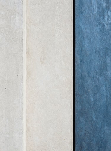 Photography of raw architectural textures. A contrast between rough off-white concrete and smooth slate blue metal. Minimalist, abstract composition, European aesthetic.