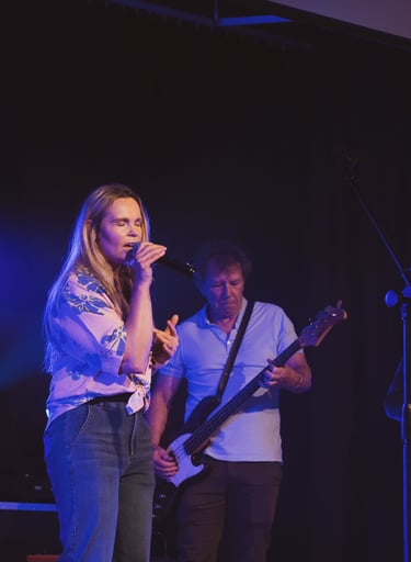 a woman singing into a microphone and a man playing the guitar